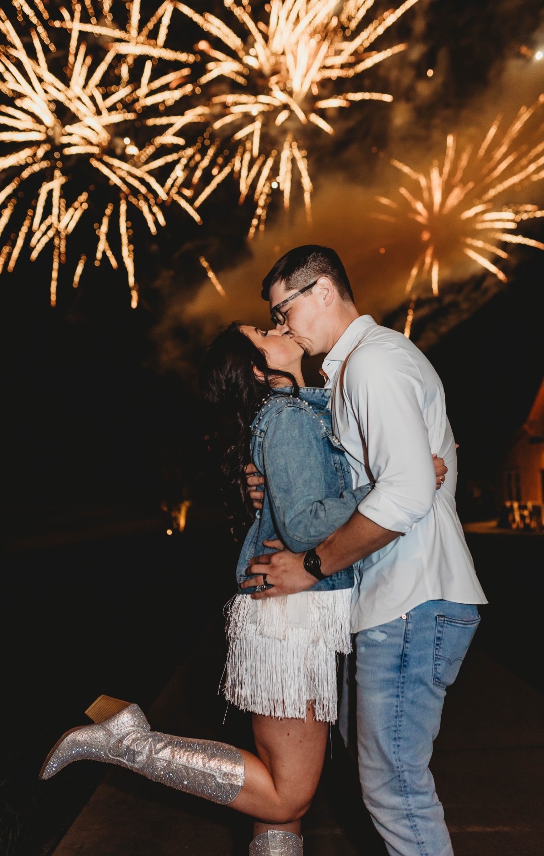 Couple kissing beneath a massive golden fireworks display at their wedding
